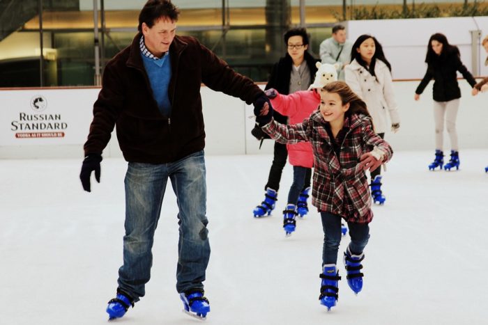 A man and his daughter ice-skating. 