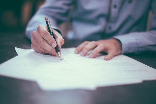 image of a person signing paperwork to represent lease signing. 