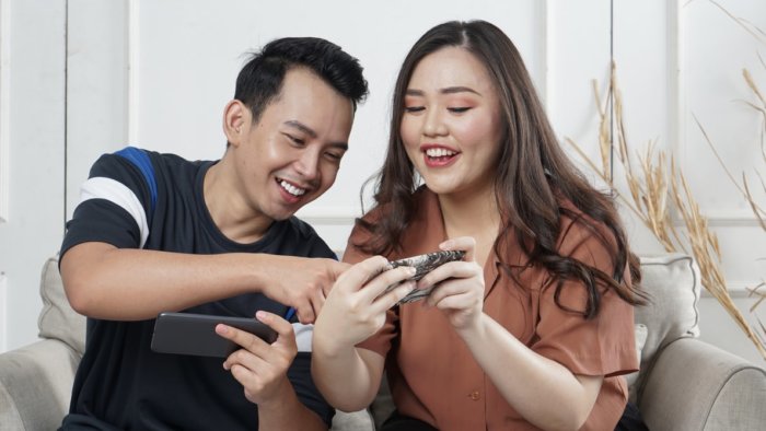 A man and woman looking at their phones and smiling. 