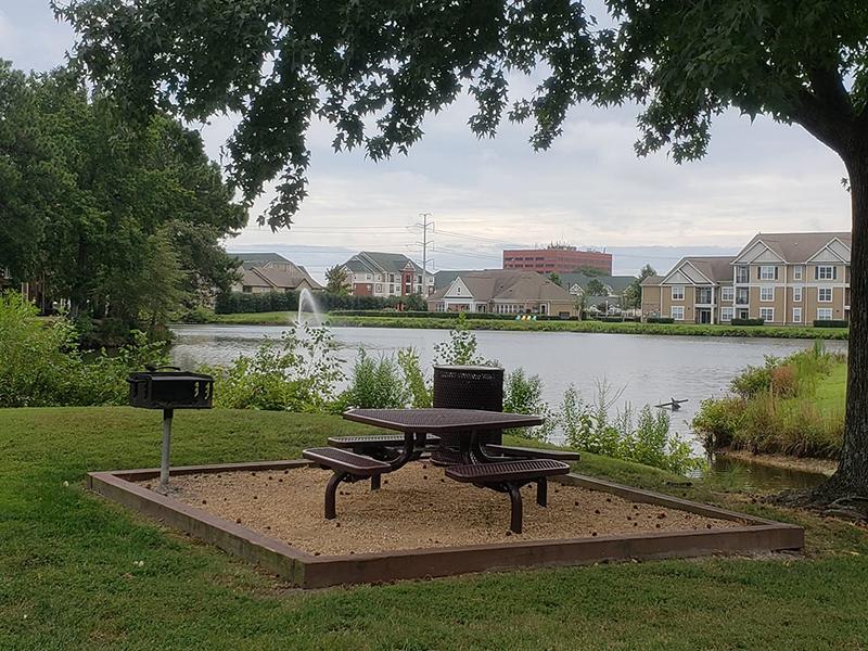 Community picnic area with table and benches sitting next to the pond in the center of Bridgewater at Town Center Apartments.