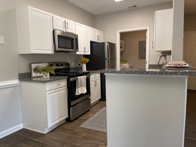 Model kitchen with wood-style flooring and an attached laundry room at The Lakes at Town Center Apartments.