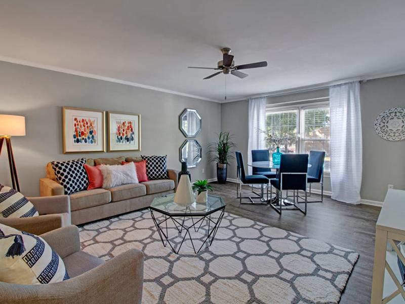Windows light the living room in an apartment in Newport News furnished with a couch and upholstered chairs.