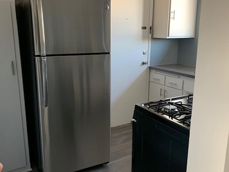 Los Angeles Apartments - Verdugo Mesa Apartments Kitchen with Wood-Style Flooring, Stainless Refrigerator, and White Cabinetry
