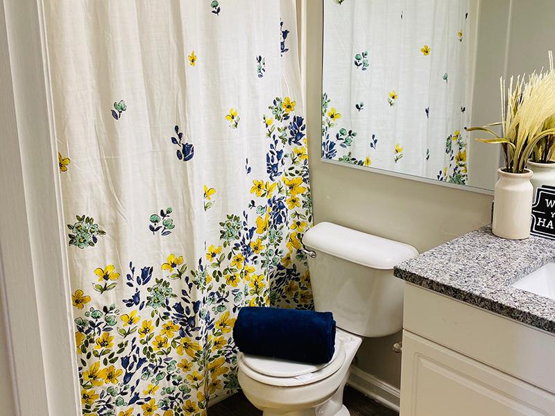 Model bathroom with tub shower and toilet at The Lakes at Town Center Apartments.