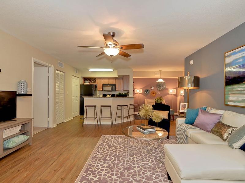 Furnished model living room looking into the kitchen and dining area.