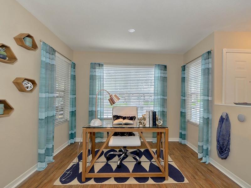 Furnished solarium has a desk and chair with lots of natural lighting.