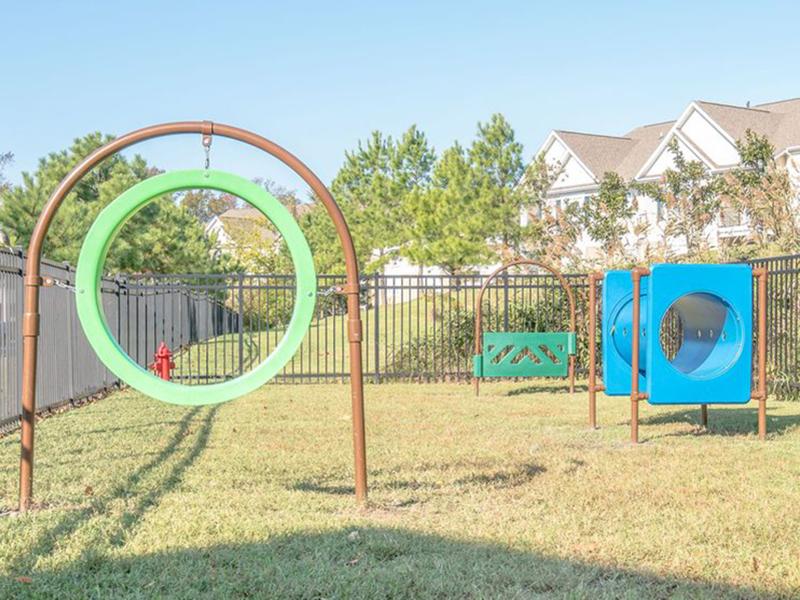 The fenced in bark park has an agility course for your dog at The Lakes at Town Center Apartments.