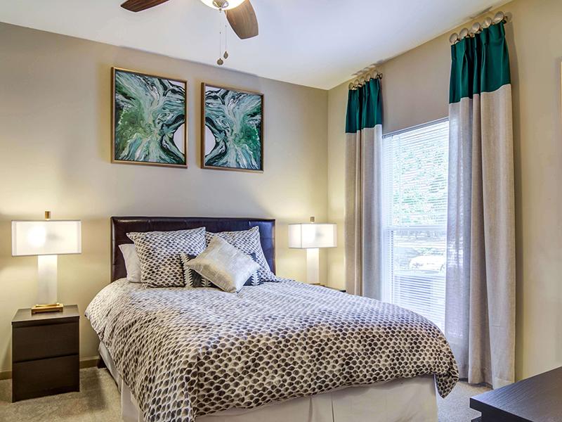 Model bedroom with a large bed and 2 nightstands in the apartments at Eagle's Brooke.