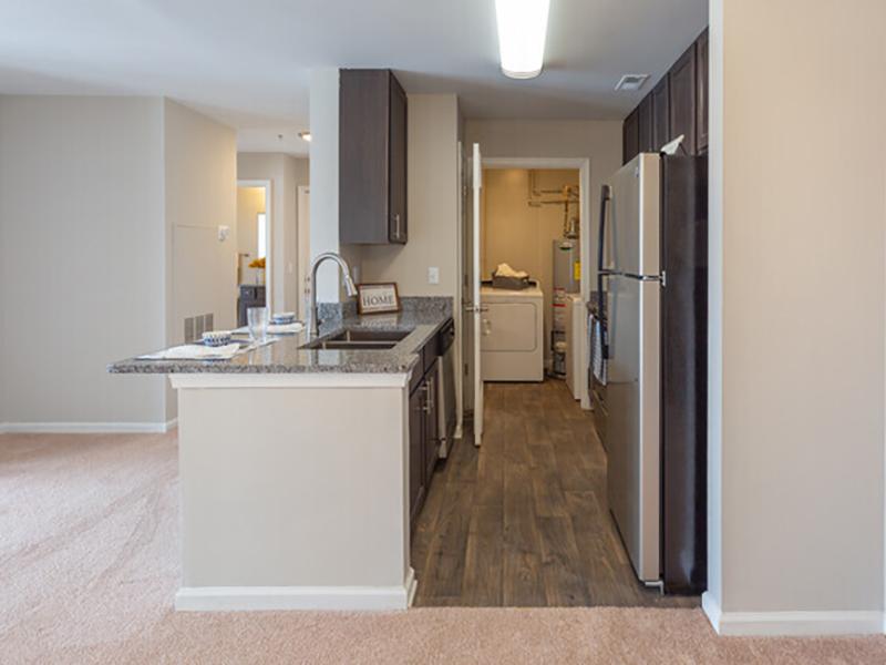 Model galley kitchens have wood-style flooring and stainless steel appliances with attached laundry room.