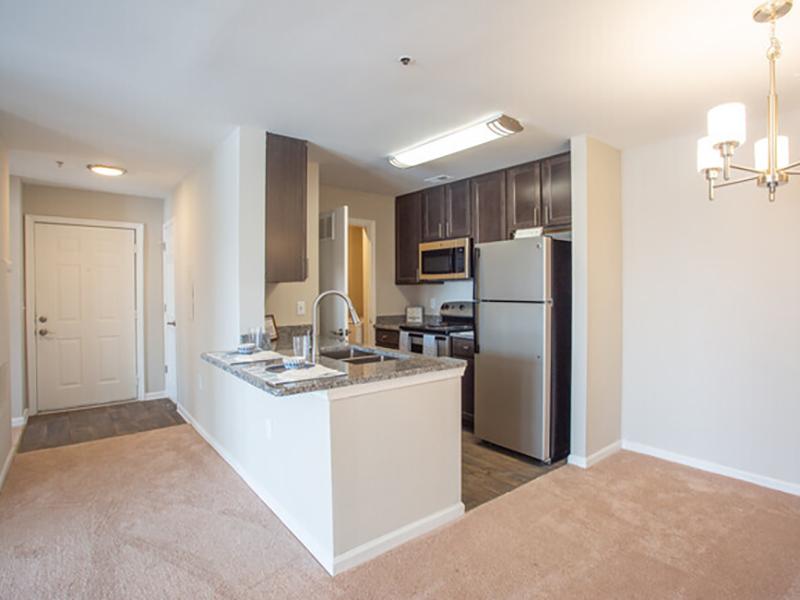 Model kitchen with a breakfast bar has stainless steel appliances at Bridgewater at Town Center Apartments in Hampton.