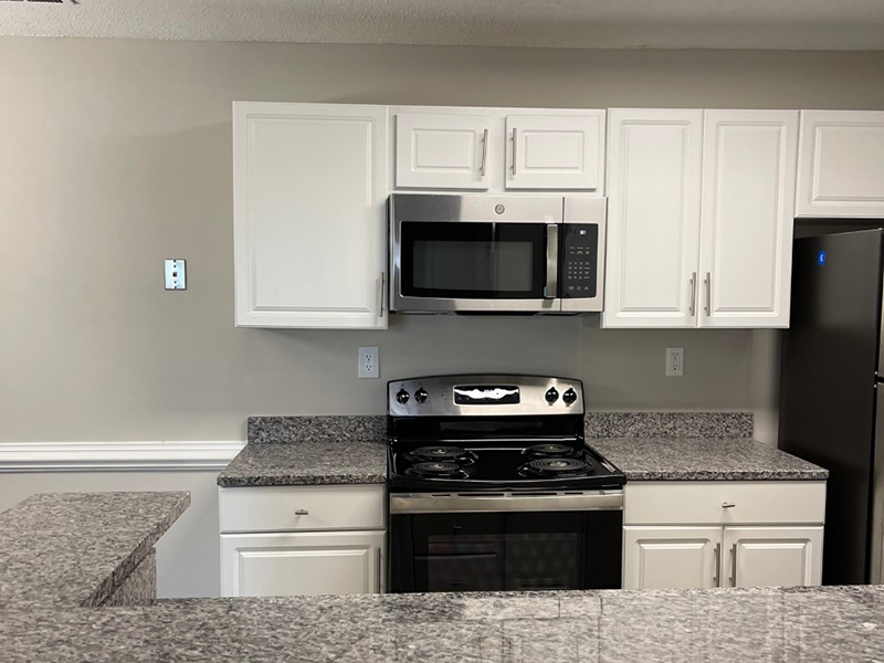 Model kitchen with stainless steel appliances and a breakfast bar at The Lakes at Town Center Apartments. 
