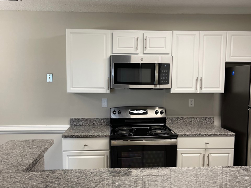 Model kitchen with stainless steel appliances and a breakfast bar at The Lakes at Town Center Apartments.