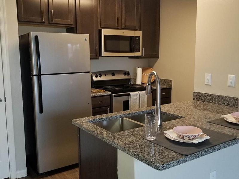Kitchens have undermount sinks with granite style countertops at Bridgewater at Town Center Apartments in Hampton. 