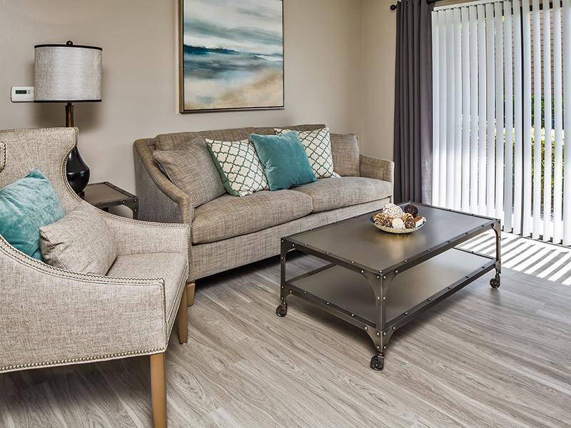 Model living room furnished with a couch and chairs with a sliding glass patio door at  Reserve at Conway Apartments. 