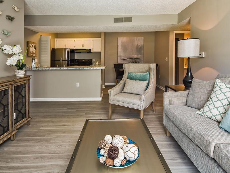 Model living room furnished with a couch and chairs looking towards the kitchen at Reserve at Conway Apartments. 