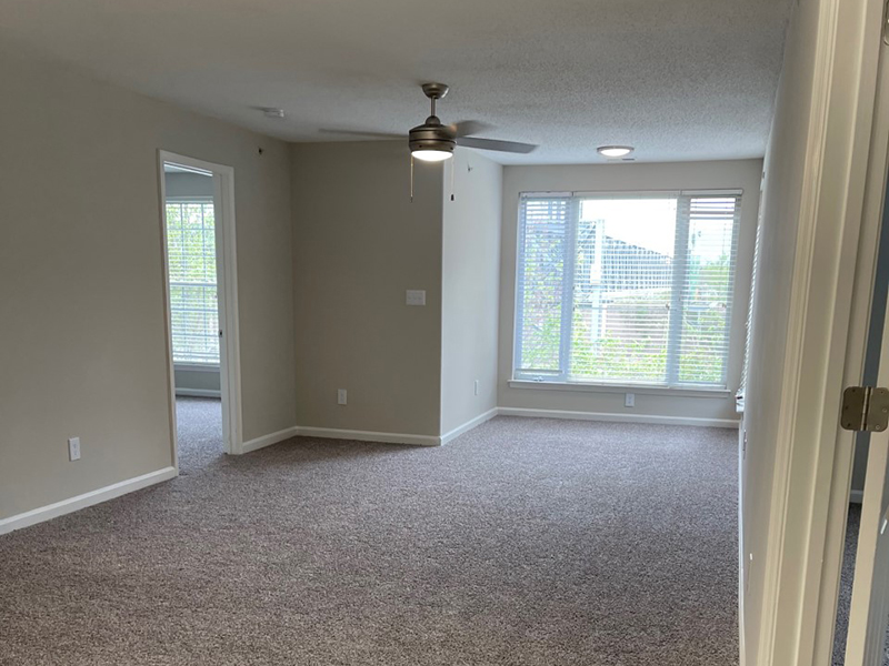 A carpeted room with double windows covered with blinds at an apartment in Hampton.