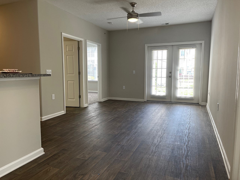 Model living room with wood-style flooring, a ceiling fan and sliding glass door in an apartment in Hampton.