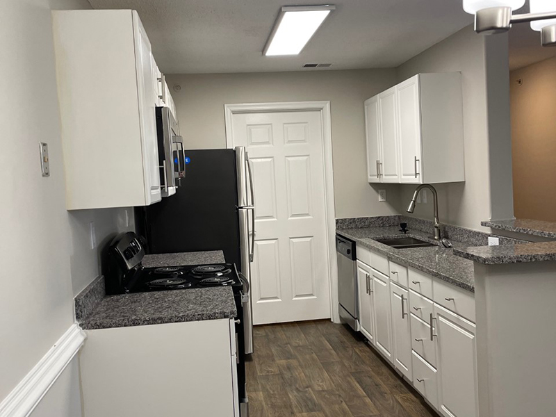 A galley style kitchen with modern appliances and a attached laundry room at The Lakes at Town Center Apartments.