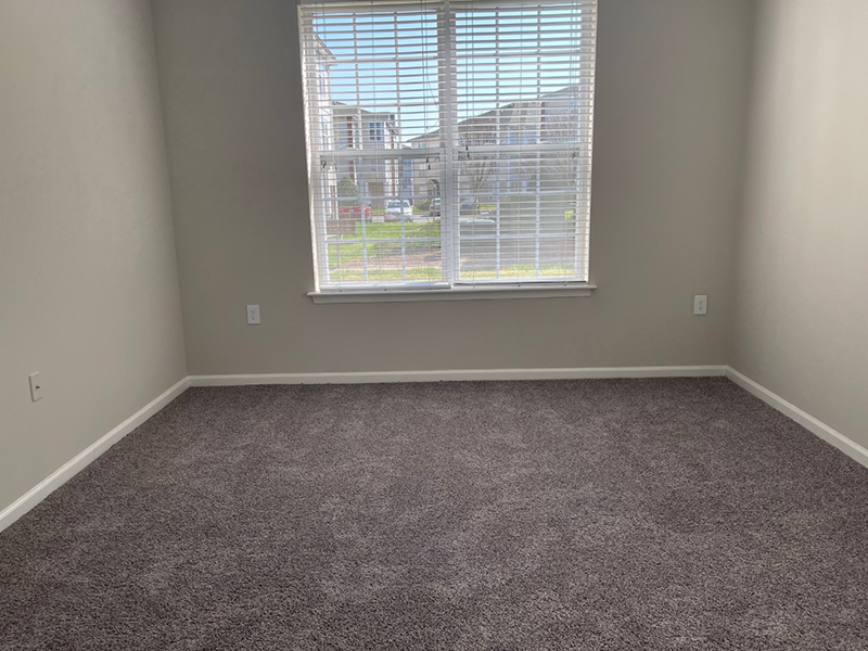 A large window with blinds in a bedroom at The Lakes at Town Center Apartments.