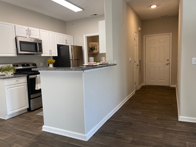 A breakfast bar overlooks the kitchen with stainless steel appliances at The Lakes at Town Center Apartments.